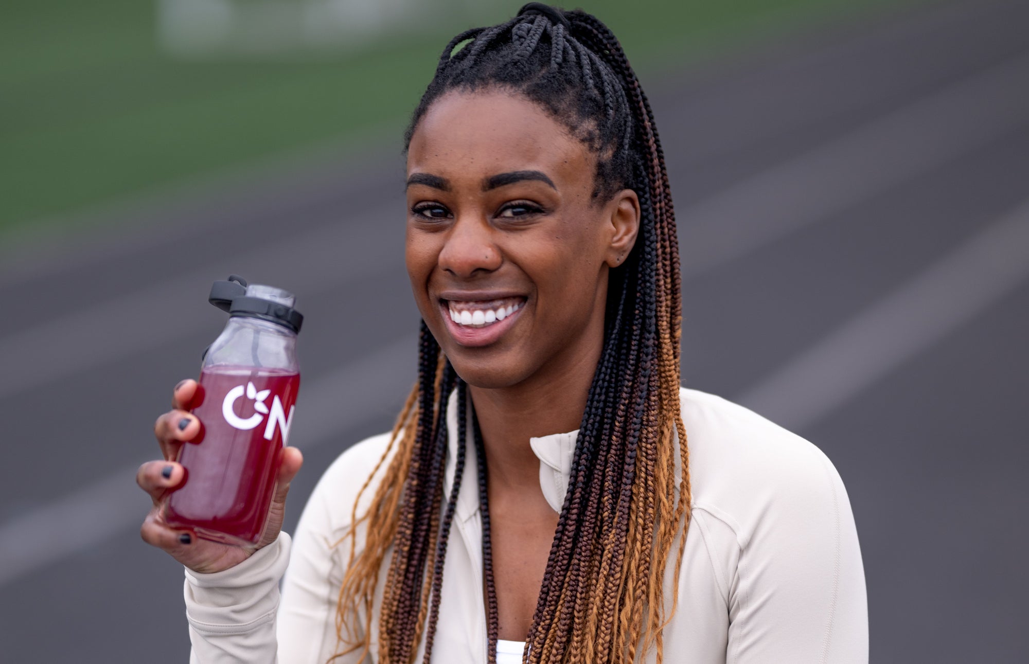 A woman with braids holds a bottle of juice, illustrating hydration tips related to electrolyte use.