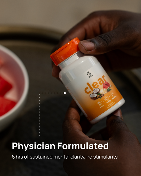 A person holds a white supplement bottle with an orange cap and orange label in their hands, with a blurred bowl of fruit in the background. Text on the image reads 'Physician Formulated' and '6 hrs of sustained mental clarity, no stimulants.
