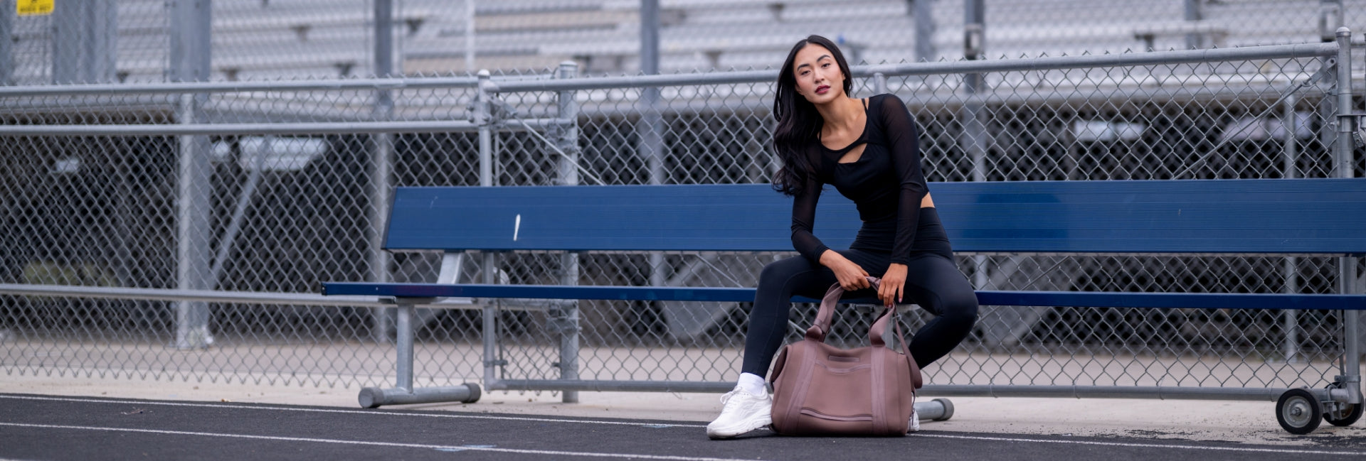 Woman sitting on a blue bench with a brown bag in an outdoor setting